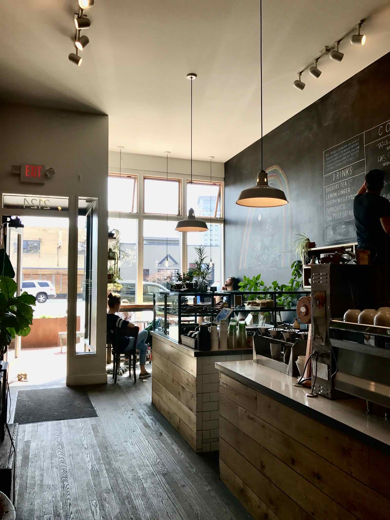 Interior de una cafetería luminosa con barra y ventanales