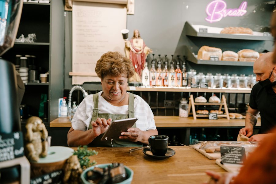 Mujer revisando una tableta en el mostrador de su cafetería