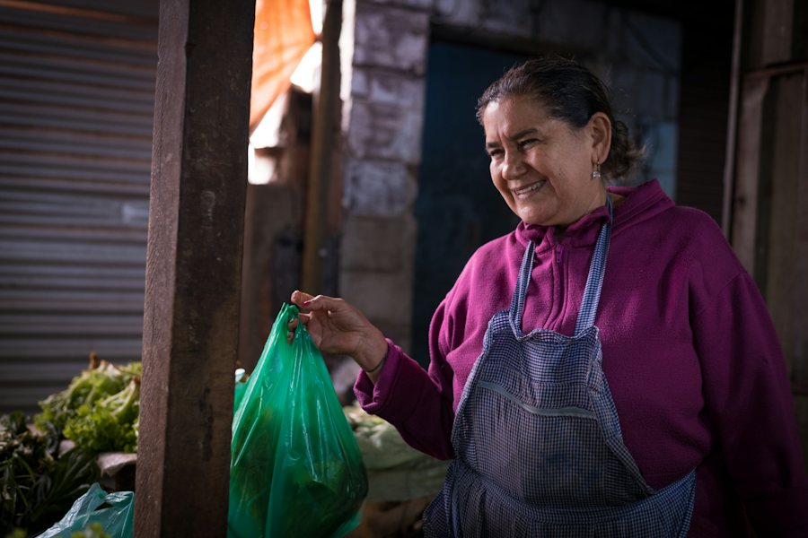 Vendedora entregando una compra en su puesto