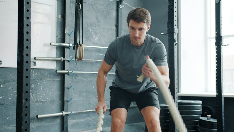 Hombre entrenando con cuerdas de batalla